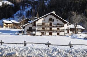 un grande edificio bianco nella neve con una recinzione di Flora Alpina apartments-Residenza Verdebjo a Gressoney-Saint-Jean