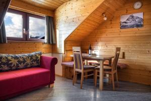 una sala da pranzo con tavolo e divano rosso di Hauserhof am Goldberg a Dellach