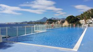 a large swimming pool next to a body of water at Apartamento Panorama 180º in Altea