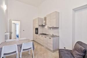 トリノにあるMoleloca - Casa Artisti 7の白いキャビネット、テーブルと椅子付きのキッチンが備わります。