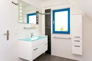 ein weißes Badezimmer mit Waschbecken und Fenster in der Unterkunft Ferienwohnungen Ostrea & Rugia in Breege