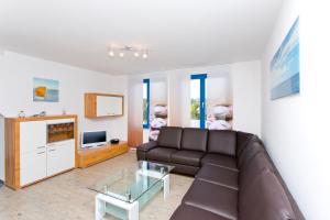 ein Wohnzimmer mit einem braunen Sofa und einem TV in der Unterkunft Ferienwohnungen Ostrea & Rugia in Breege