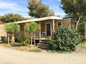 a small wooden house with a porch and stairs at Camping Paradis 4 étoiles Au Port de L'Houmeau - La Rochelle in LʼHoumeau