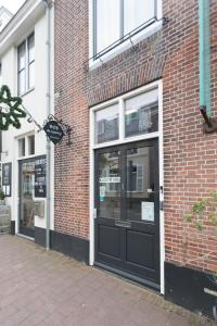 a brick building with a black door on a sidewalk at B&B de Lijsterhof in Domburg