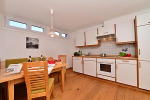 een keuken met witte kasten en een houten tafel bij Ferienwohnungen Thannheimer in Oberstdorf