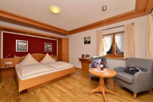 een slaapkamer met een bed, een stoel en een tafel bij Ferienwohnungen Thannheimer in Oberstdorf