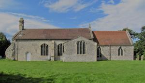 an old stone church on a grass field at The Three Horseshoes in Warham
