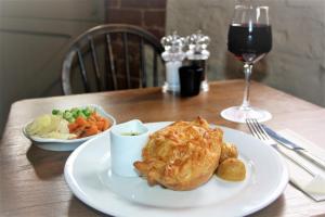 a table with a plate of food and a glass of wine at The Three Horseshoes in Warham