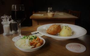 a table with two plates of food and a glass of wine at The Three Horseshoes in Warham