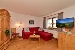 オーベルストドルフにあるHaus Am Mühlenwegのリビングルーム(赤いソファ、テレビ付)