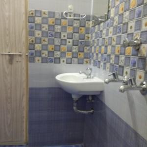 a bathroom with a white sink and blue tiles at Manjira Lodge in Guruvāyūr