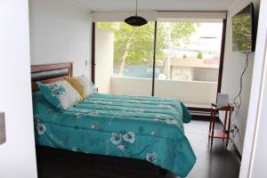 Un dormitorio con una cama con sábanas verdes y una ventana en Departamentos Parts Concepción, en Concepción
