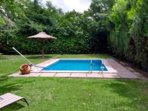 a swimming pool with an umbrella in a yard at Alonso Chacras Lodge in Chacras de Coria