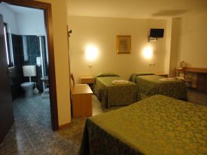 パストレンゴにあるHotel La Caricaのベッド3台とバスルームが備わるホテルルームです。