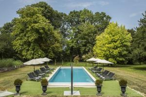 a swimming pool with lounge chairs and umbrellas at Les Lodges du Château près La Rochelle in Saint-Christophe