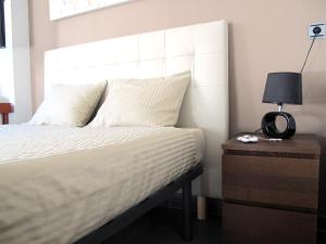 グラナダにあるApartamento ALDAMYのベッド(ナイトスタンドの横に白いヘッドボード付)