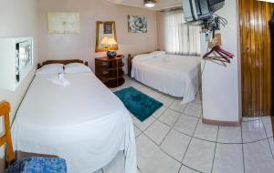 um quarto com duas camas e uma televisão em Hotel Laura's House em Coco