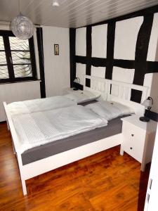 Cama blanca grande en habitación con suelo de madera en Gasthaus Burgkeller, en Limburg an der Lahn