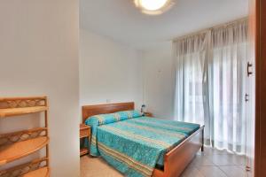 a small bedroom with a bed and a window at Residenza Cedri in Lignano Sabbiadoro