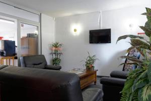 een woonkamer met een bank en een tv aan de muur bij Fasthotel Tarbes Séméac - Un hôtel FH Confort in Séméac