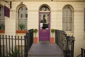 a purple door on a house with a fence at The Oriental - Guest House in Brighton & Hove
