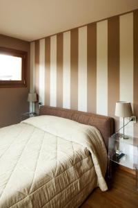 a bedroom with a bed with striped walls and two lamps at Elegante attico sulle piste di Pila in Pila