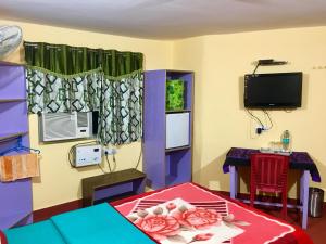 a room with a bed and a table and a tv at Kundanbazar Guest House in Bodh Gaya