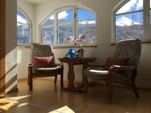 2 stoelen en een tafel in een kamer met ramen bij BnB Guesthouse Lusi in Frauenkirch