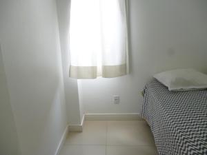 a bedroom with a bed and a window at Flat no Farol in Salvador