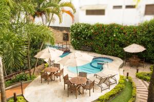 an outdoor patio with tables and umbrellas and a pool at Hotel Ilhas da Grécia in Guarujá