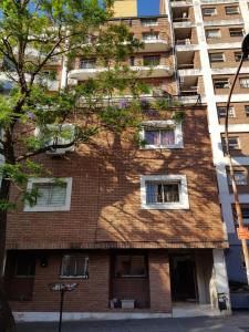 un edificio de apartamentos con un árbol delante de él en Apartamento Carlucci en Córdoba