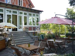 un patio avec des tables et des parasols en face d'un bâtiment dans l'établissement Gästehaus Musestieg, à Thale