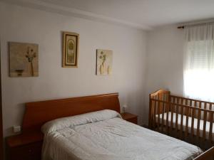 イスラ・クリスティナにあるPiso Vacacional Isla Cristinaのベッドルーム(ベッド1台、ベビーベッド1台付)