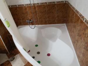 bañera blanca con decoración colorida en el suelo en Piso Vacacional Isla Cristina, en Isla Cristina
