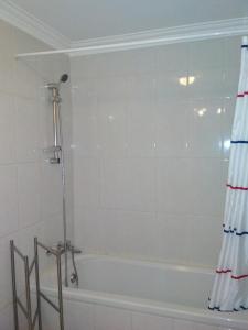 y baño con bañera y cortina de ducha. en Maison Blanche en Guizande