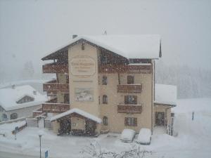 un edificio cubierto de nieve con coches aparcados delante en Hotel Seggiovia, en Folgaria