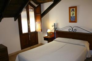 een slaapkamer met een wit bed en een raam bij Hotel Rural Huerta del Laurel in Monachil