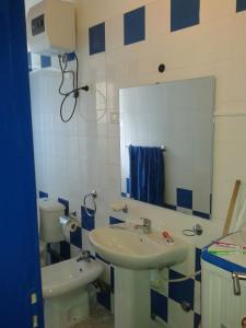 une salle de bain avec un lavabo, des toilettes et un miroir dans l'établissement Casa Azul SANTA MARIA Cape Verde, à Santa Maria