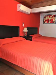 2 Betten in einem Zimmer mit roten Wänden in der Unterkunft Hotel Los Valles in Creel