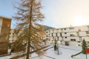 un pino en la nieve frente a un edificio en Haus Bündabrücke - Mosbacher, en Davos