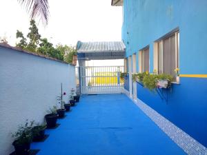 a blue building with a gate and potted plants at Apartamentos Águia Azul in Ilha Comprida