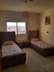 een slaapkamer met 2 bedden en een raam bij Appartement de lux 4 chambres in Oujda