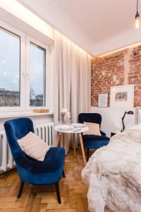 een slaapkamer met een bed en 2 stoelen en een tafel bij SleepHome Poznanska in Warschau