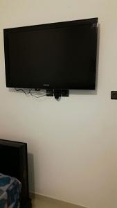 einen Flachbild-TV, der an einer Wand hängt in der Unterkunft joli appartement 4 chambres in Oujda