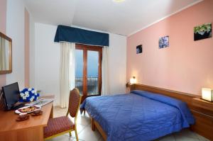 1 dormitorio con cama azul, escritorio y ordenador en Royal Hotel Montevergine en Ospedaletto dʼAlpinolo