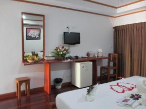 a room with a bed and a desk with a television at Lipa Bay Resort in Lipa Noi