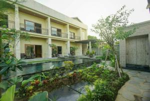 a house with a pond in front of a building at Arnaya Homestay in Kuta