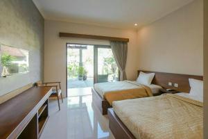 a hotel room with two beds and a balcony at Arnaya Homestay in Kuta