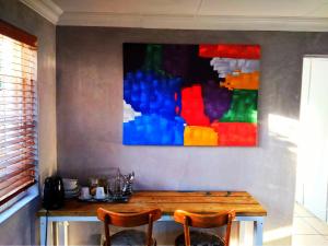 una mesa con dos sillas y un cuadro en la pared en Cottage Guesthouse en Pretoria