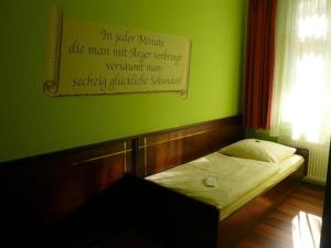 Cama pequeña en habitación verde con un cartel en la pared en Hotel am Wilhelmsplatz en Stuttgart
